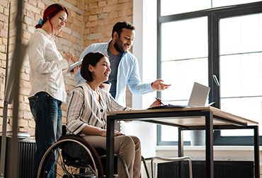 Image of a group of educators having a conversation, two are standing, and one is in a wheelchair  