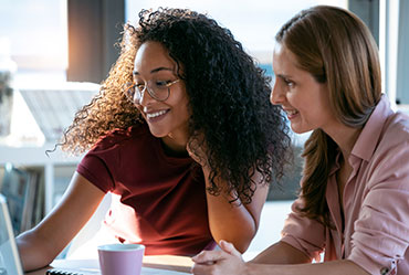 Image of two educators sitting next to each other and looking at a screen