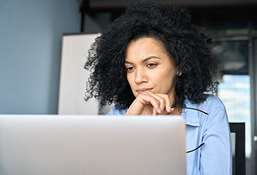 An individual using their laptop, looking reflective.