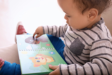 A young child is pointing to a page in a children’s book.