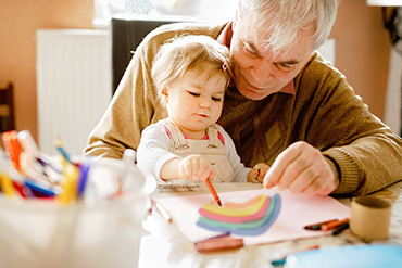 An older adult is colouring with a young child.