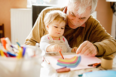 Une personne âgée et un jeune enfant colorient ensemble.