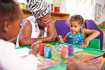 An RECE is painting with two children.