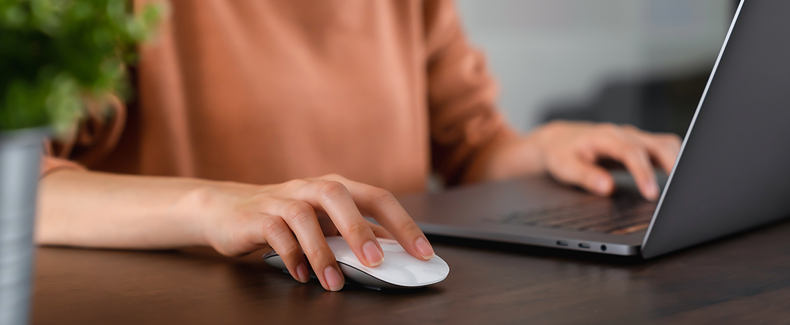 A person working on a laptop using both, the mouse and keyboard.